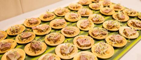 A table with round, flatbreads topped with a pinkish food item and garnished with sprouts, arranged on a green leaf-like surface.