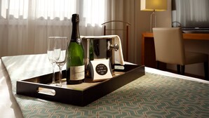 A tray with a bottle of Castello D'Oro wine, two glasses, and a chocolate bar on a bed with patterned bedding. - Hotel Exe Getafe (Getafe)