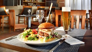 A restaurant setting with a table set for a meal, including a burger, salad, and a glass of beer. - Hotel Exe Getafe (Getafe)