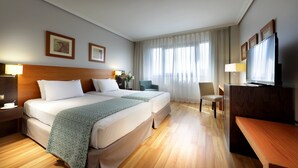 A hotel room with two beds, a desk, a TV, and a chair. - Hotel Exe Getafe (Getafe)