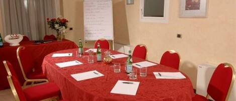 A conference room with a red table and chairs, a whiteboard, and a window with a view.