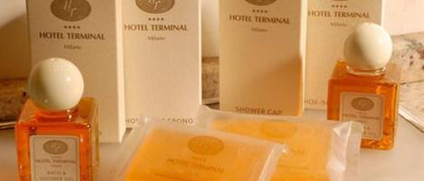 Hotel toiletries including a shower cap, bath & shower gel, and a bottle of lotion.