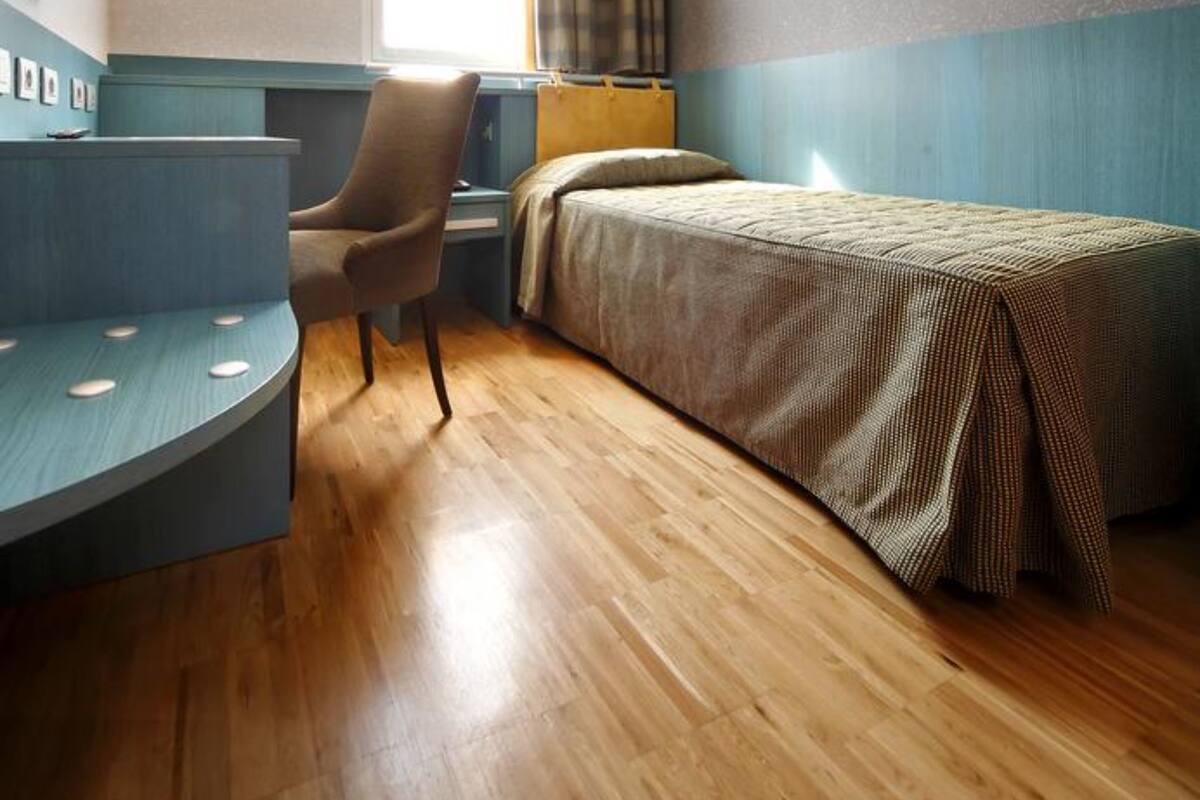A hotel room with a bed, a desk, a chair, a television, and a window with curtains.