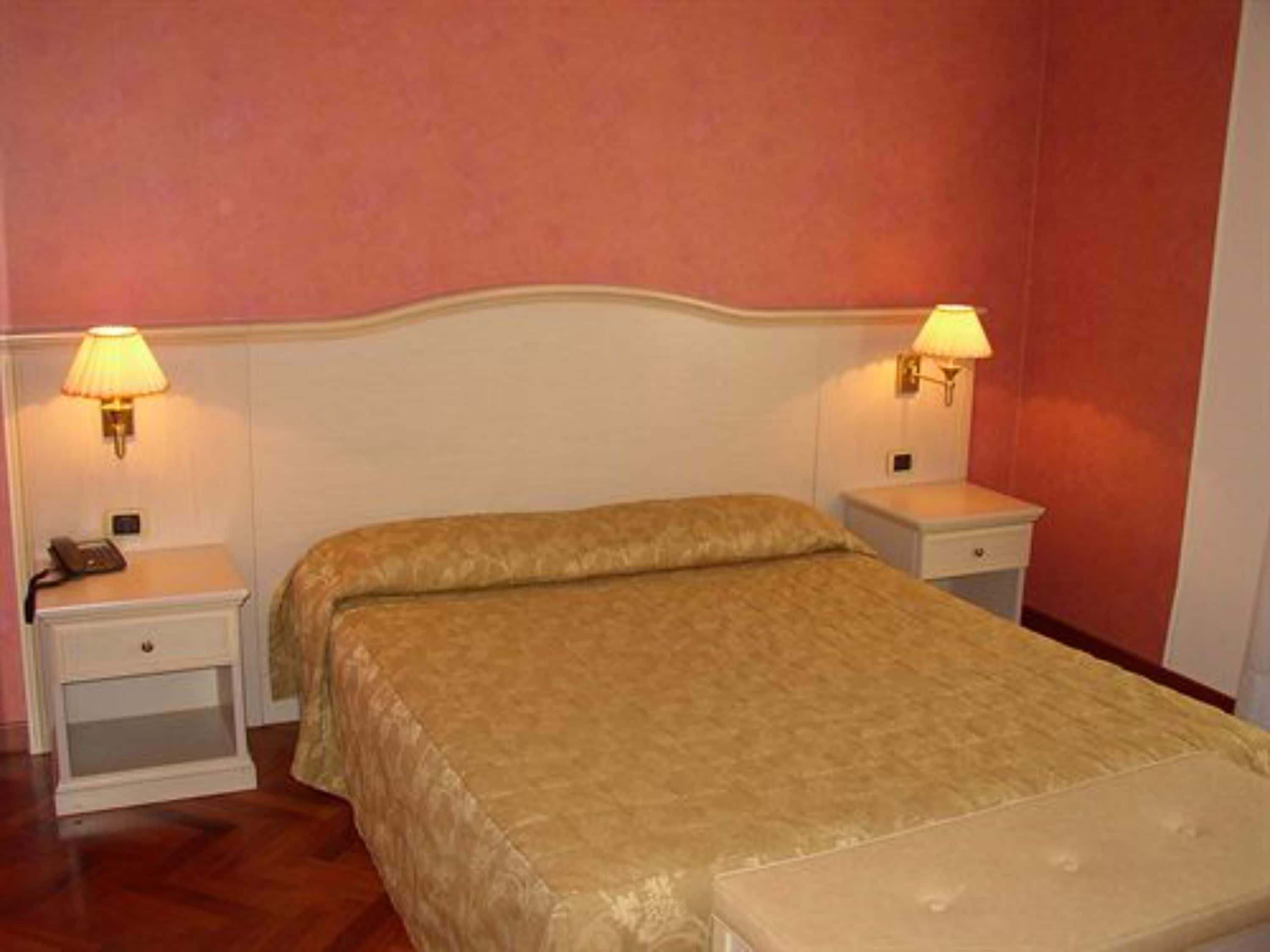 A bedroom with a bed, two bedside tables, and two wall-mounted lamps.