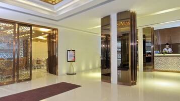 A hotel lobby with a reception desk, decorative panels, and a clear floor.