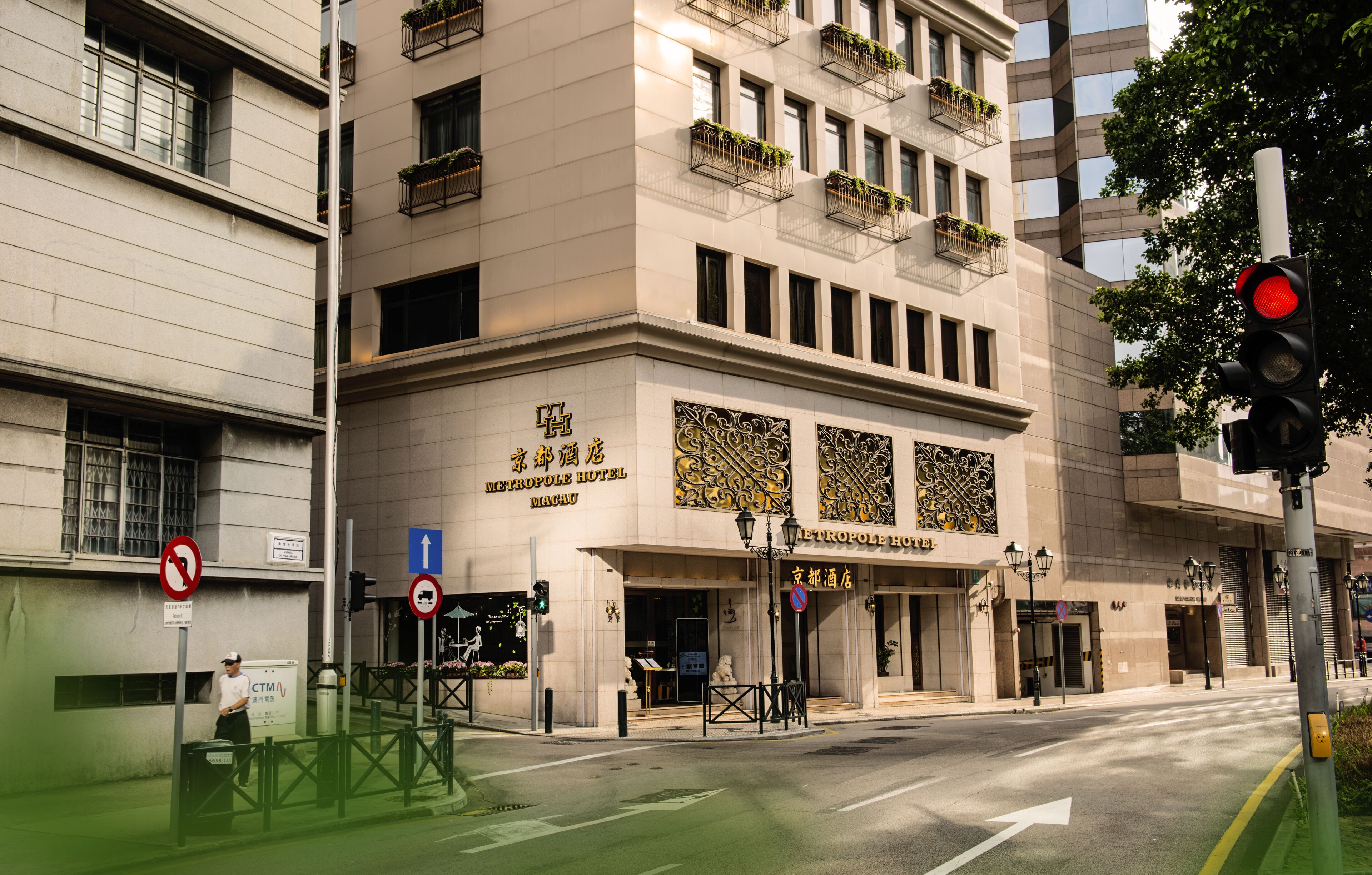 Un hotel de fachada moderna, con varios pisos y balcones adornados con plantas.
