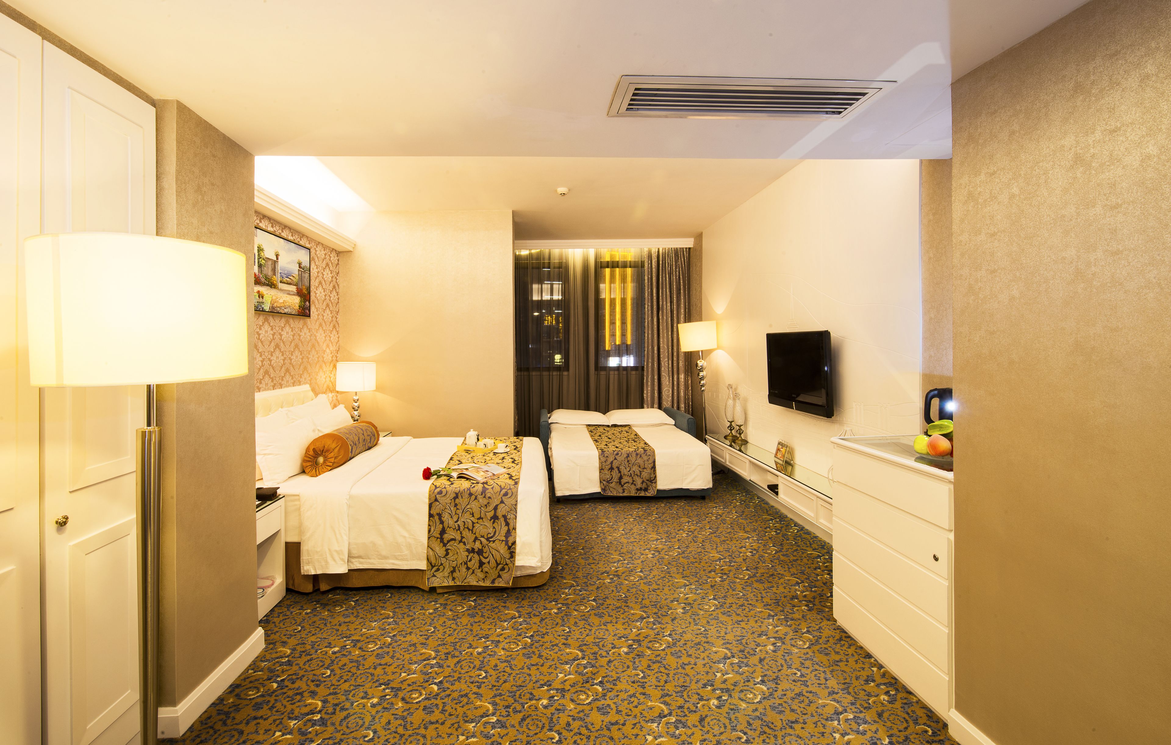 Habitación de hotel con dos camas, televisión, escritorio y baño.