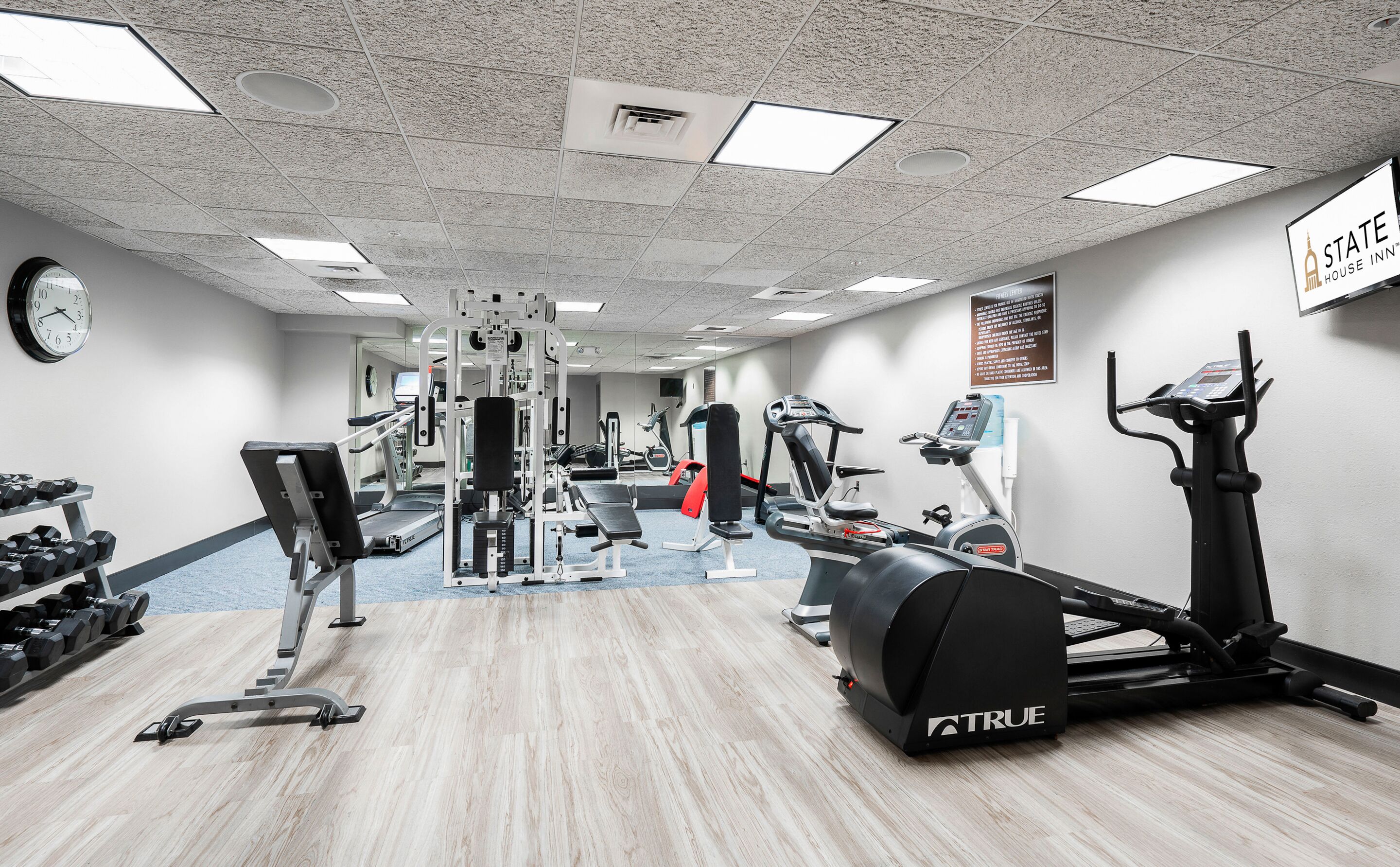 A gym with various exercise equipment, including treadmills, weight machines, and dumbbells.