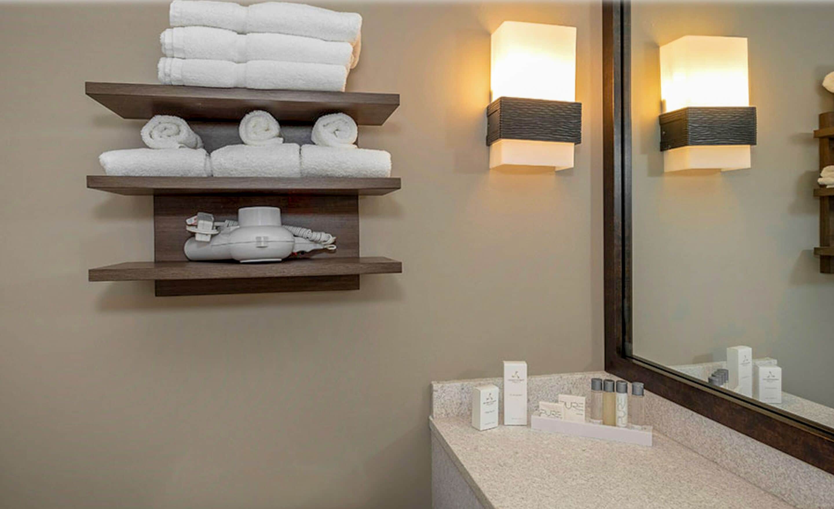 A bathroom with a vanity, towel racks, and a mirror.