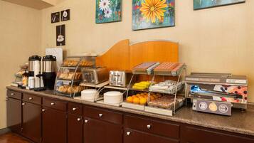 A buffet setup with various food items and a touchless pancake maker.
