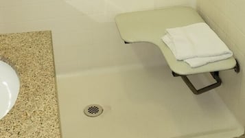 A small, private shower stall with a grab bar, a white sink, and a towel rack.