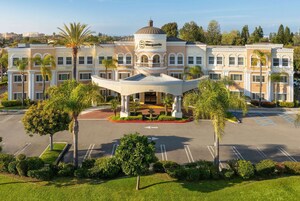 Un hotel grande de varios pisos con una estructura cúpula central, un estacionamiento amplio y jardines bien cuidados.