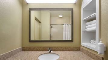 Un bagno con lavabo in granito, uno specchio e un porta asciugamani con asciugamani.