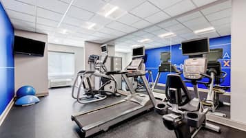 A modern gym with treadmills, elliptical machines, and exercise balls.