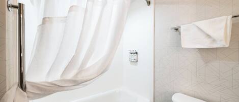 A bathroom with a bathtub, a toilet, and a shower curtain.