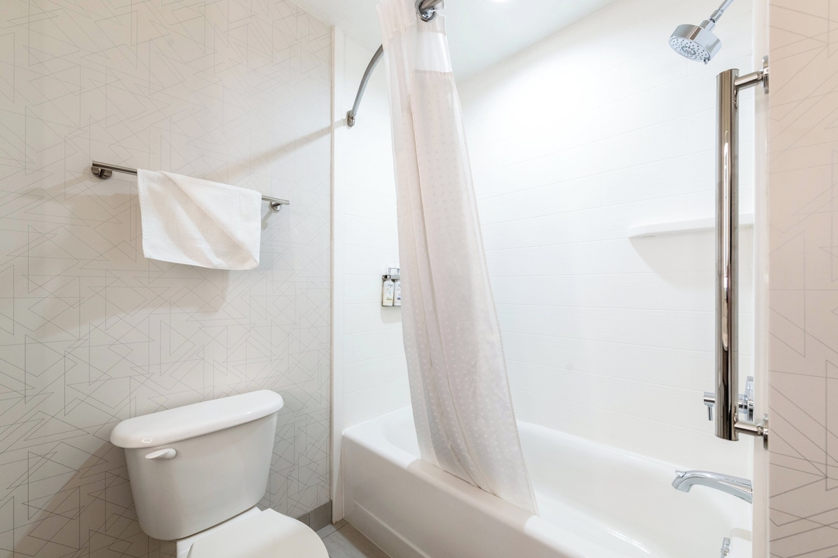 Une salle de bain comprenant des toilettes, une douche avec un rideau et une baignoire.