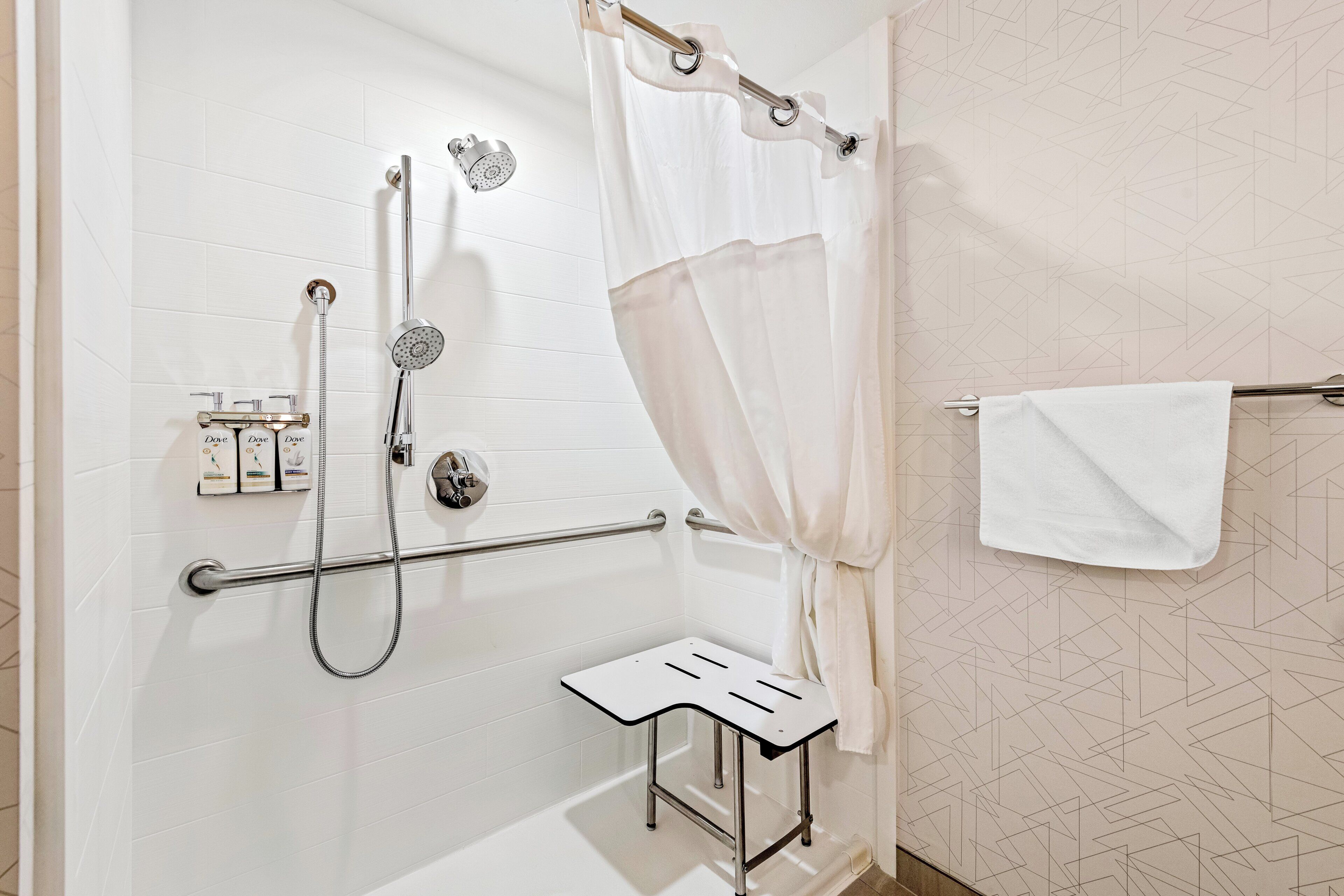 Un baño moderno con ducha, un perchero y una pequeña mesa.