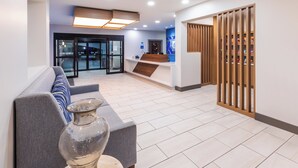 A modern lobby with a reception desk, seating area, and a decorative wooden partition. - Holiday Inn Express Harvey-Marrero by IHG (Harvey)