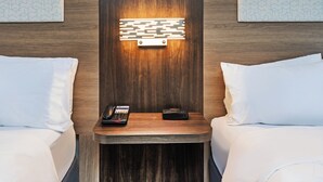 A hotel room with two beds, a nightstand with a phone and a portable charger, and a wall-mounted light fixture. - Holiday Inn Express Harvey-Marrero by IHG (Harvey)
