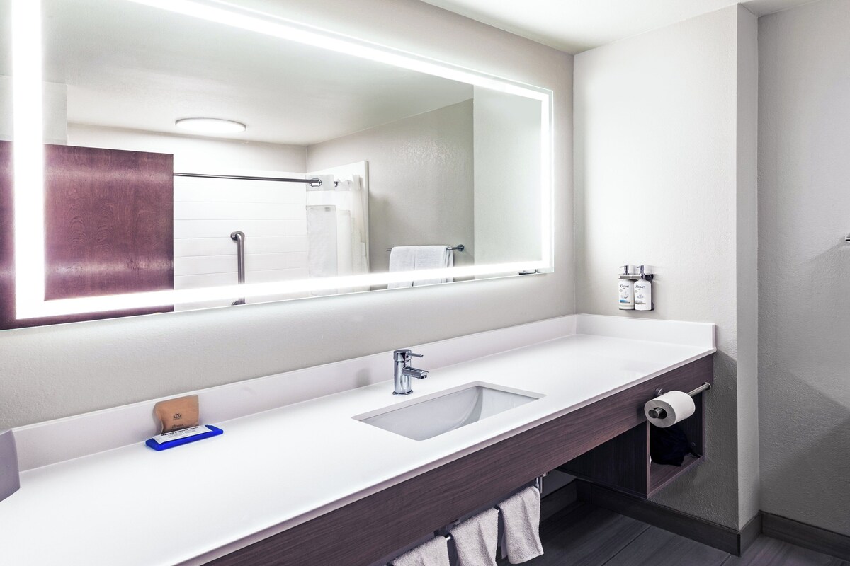 A modern bathroom with a large mirror, a sink, and a towel rack.