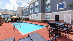 A hotel with a swimming pool, outdoor seating, and a brick facade. - Holiday Inn Express Harvey-Marrero by IHG (Harvey)