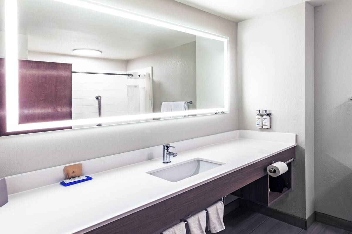 A modern bathroom with a large mirror, a sink, and a towel rack.
