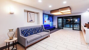 A modern lobby with a grey sofa, a vase on a small table, and a map on the wall. - Holiday Inn Express Harvey-Marrero by IHG (Harvey)