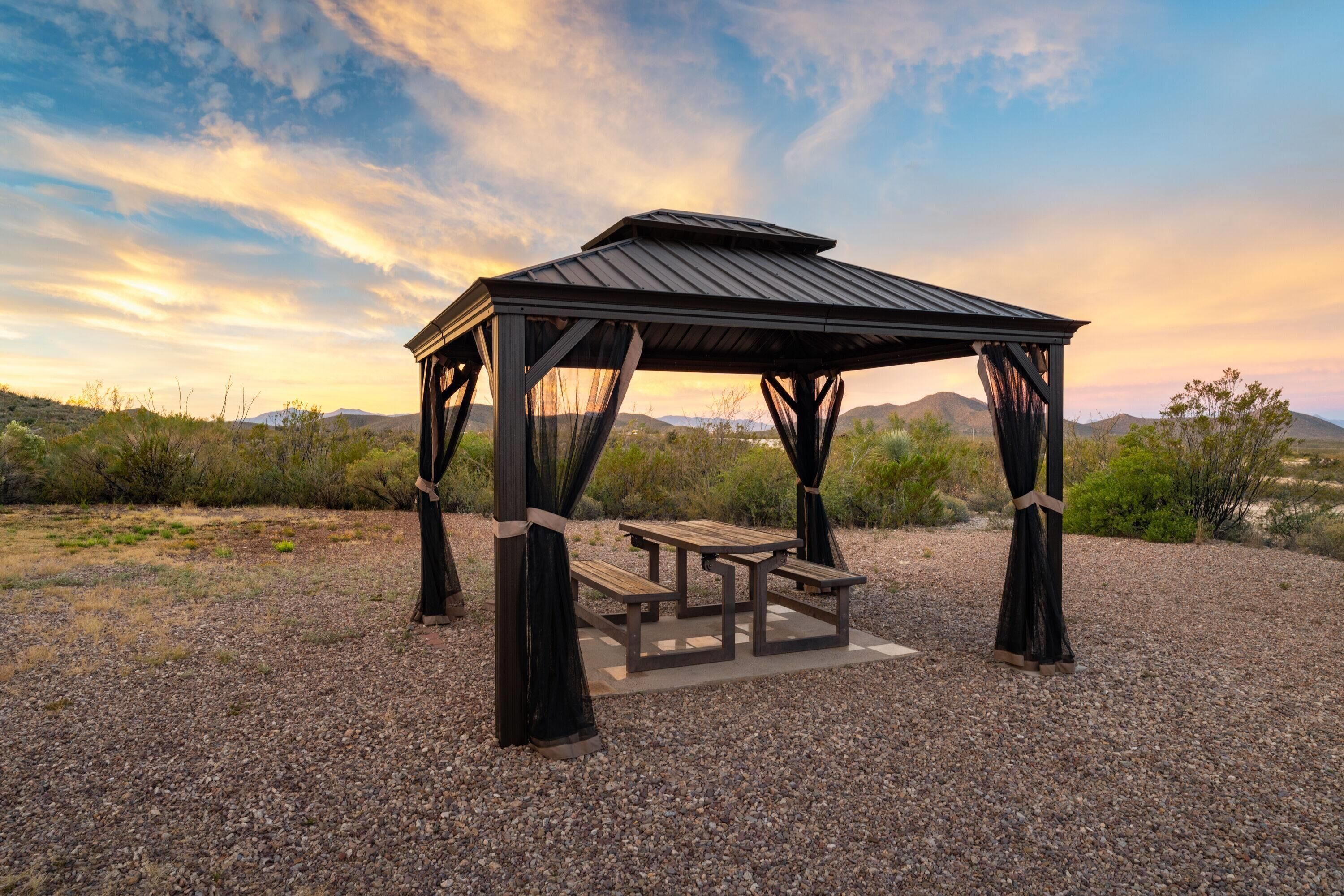 Um gazebo com uma mesa de piquenique em uma paisagem desértica.