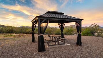 Um gazebo com uma mesa de piquenique em uma paisagem desértica.