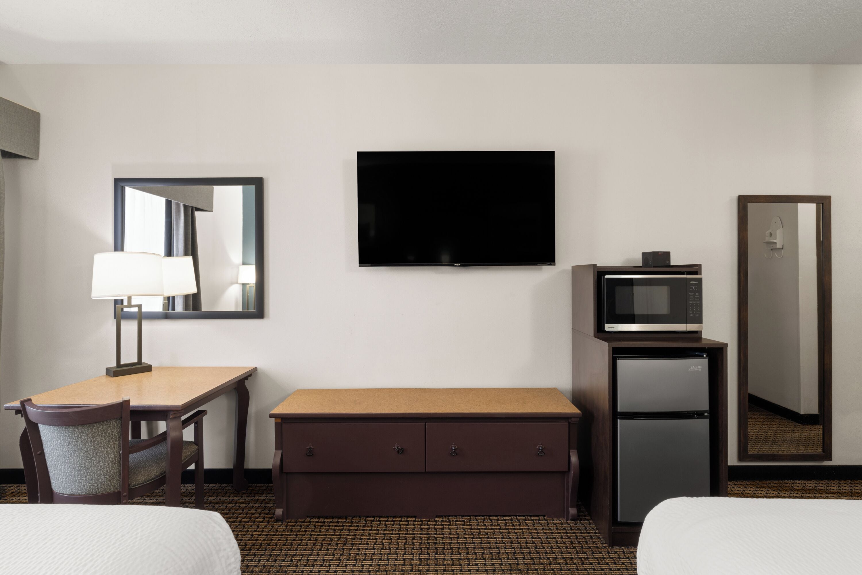 Une chambre d’hôtel équipée d’un lit, d’un bureau avec une lampe, d’une télévision, d’un four à micro-ondes et d’un mini-bar.
