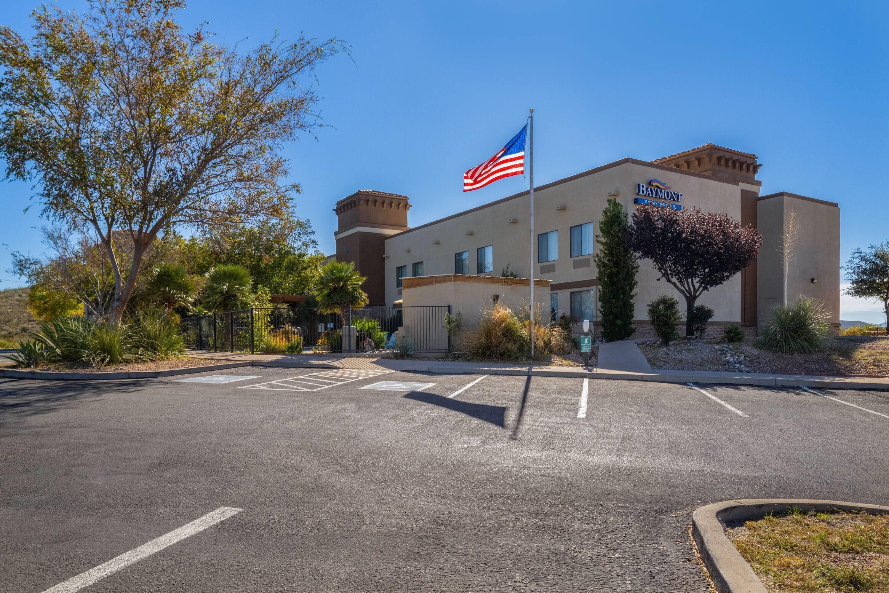 A hotel with a flagpole, parking lot, and landscaping.
