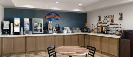 Un rincón para desayunar con una mesa y sillas de madera, una estación de café y un letrero que dice "Breakfast Corner".