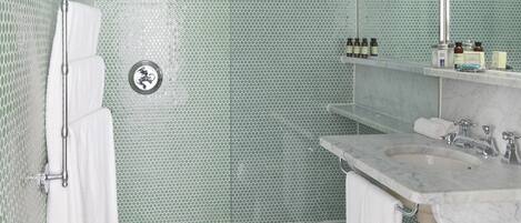 Un baño con ducha envuelta en vidrio, lavamanos de mármol y un espejo grande.