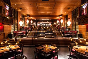 A restaurant with a central stage, wooden decor, and candle-lit tables.