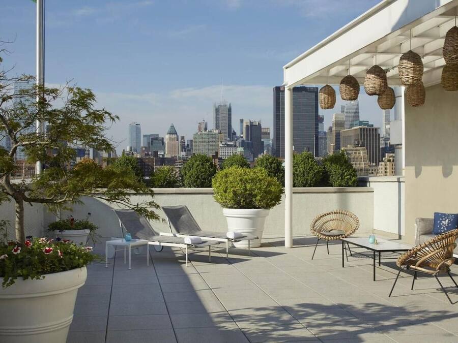 Terraza en la azotea con sillones de descanso, plantas en macetas y vistas al horizonte urbano.