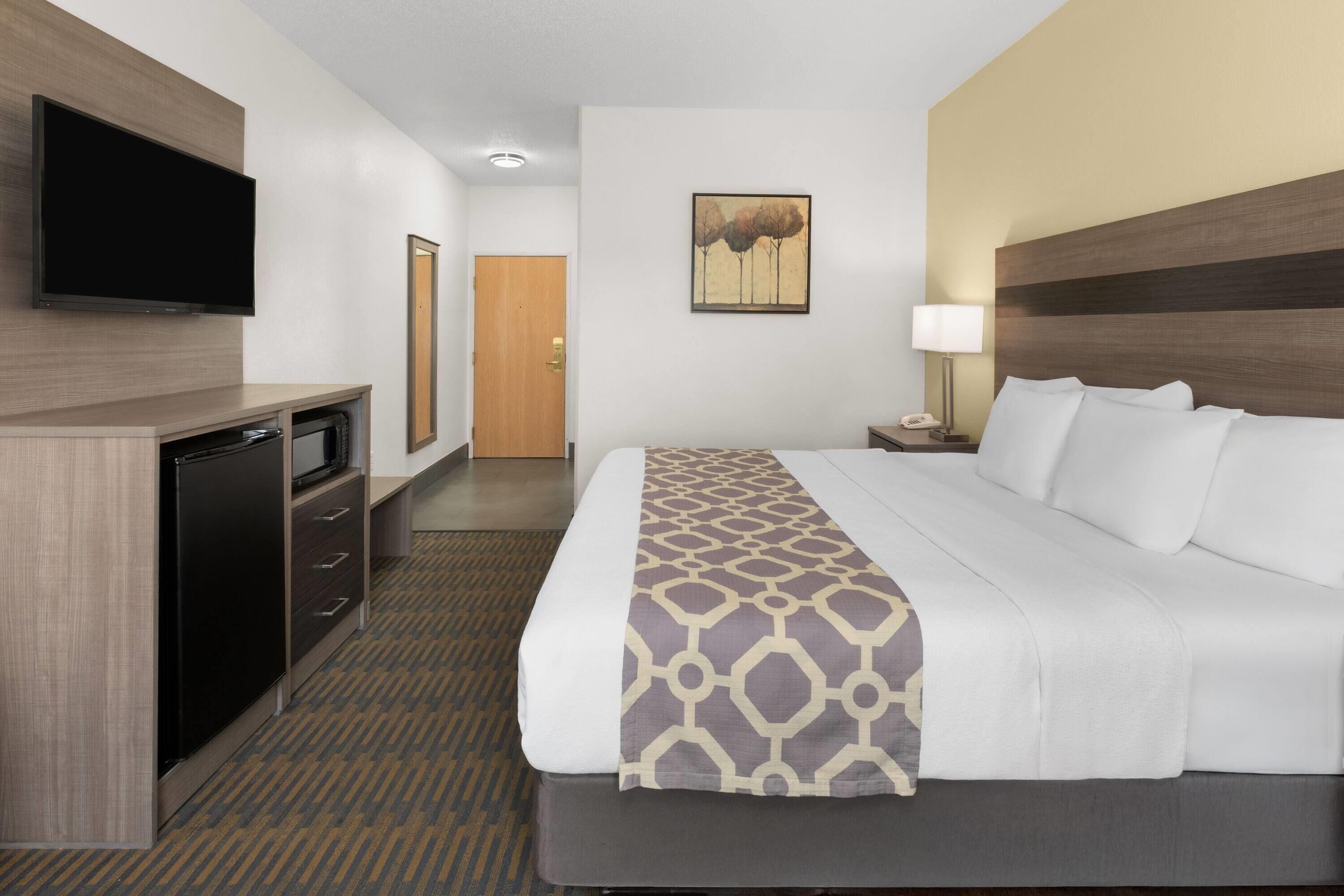 A hotel room with a bed, a TV, a desk, and a door.