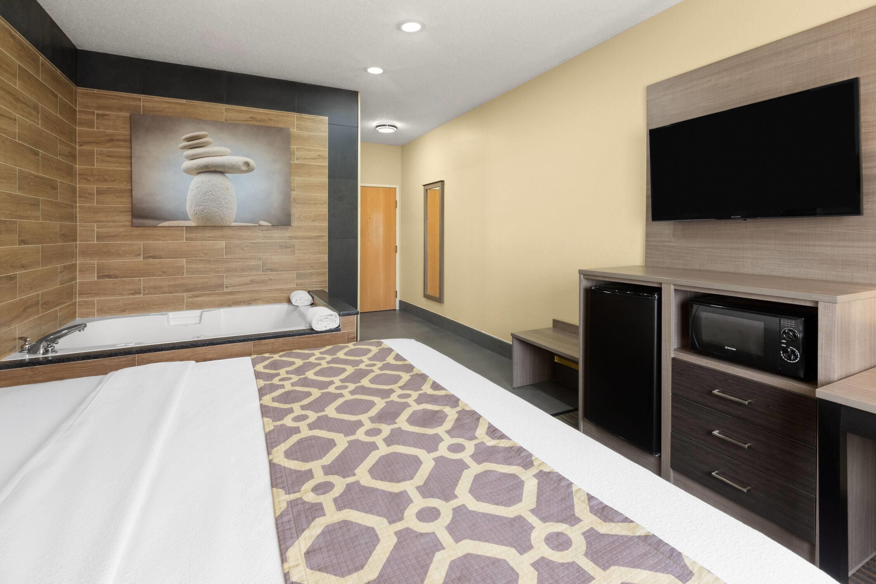 Een moderne hotelkamer met een groot bed, een ingebouwde televisie, een magnetron en een klein zithoekje.