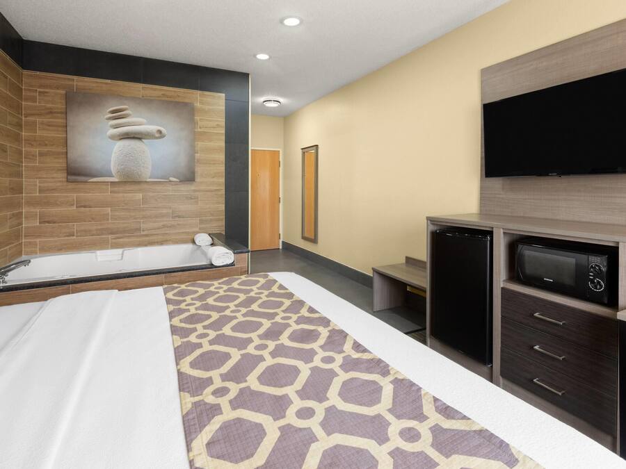 A modern hotel room with a large bed, a built-in TV, a microwave, and a small seating area.