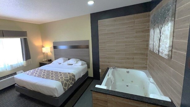 Une chambre d’hôtel avec un lit, une grande baignoire et un tableau au mur.