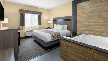 Una habitación de hotel con cama, baño con bañera, escritorio y ventana con cortinas.