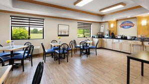 Un espace pour prendre le petit-déjeuner avec des tables et des chaises, un coin cuisine et une vue sur l’extérieur.