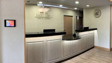 A reception area with a counter, a clock, and a sign for 'Baymont Inn & Suites'.