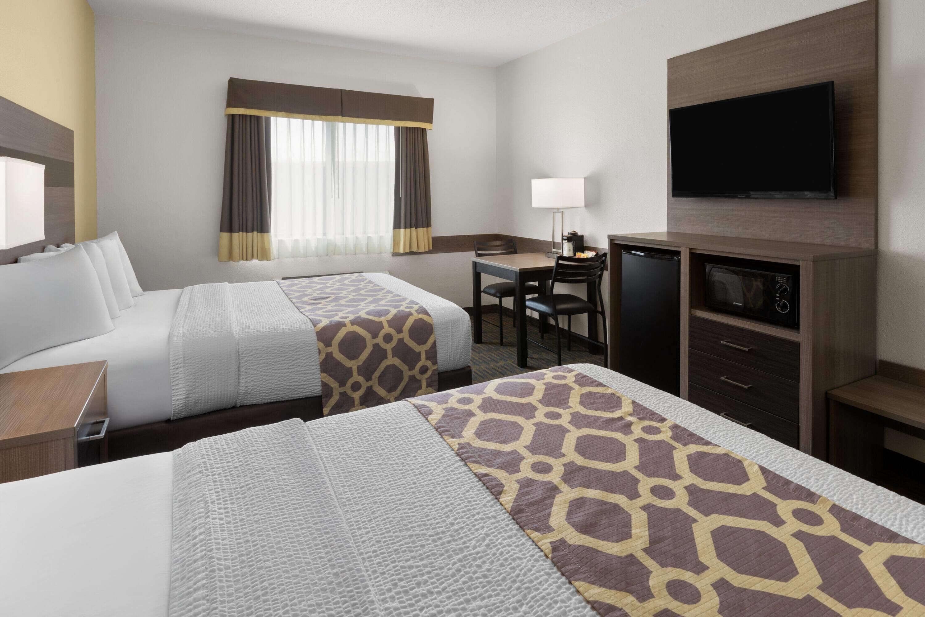 Habitación de hotel con dos camas, un escritorio con silla, televisión y microondas.