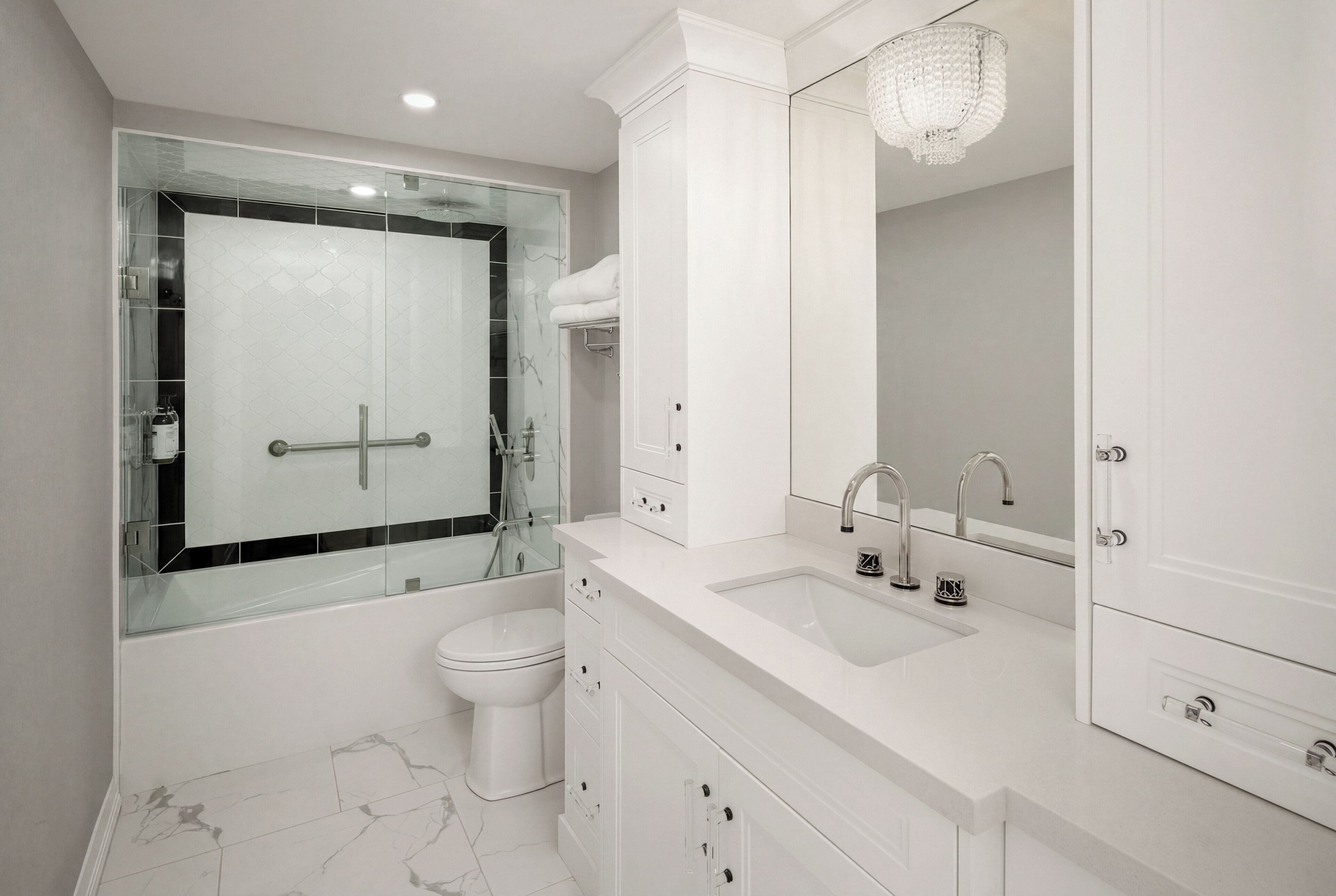 Un bagno moderno con cabina doccia in vetro, lavabo bianco e uno specchio grande.