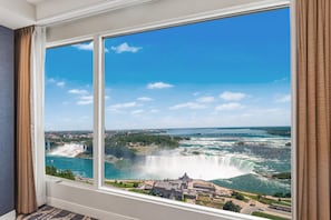 A room with a large window overlooking a waterfall and a view of a cityscape. - Hyatt Regency Niagara Falls Fallsview (Niagara Falls)