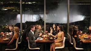 Un grupo cenando en una mesa con vista a una cascada.
