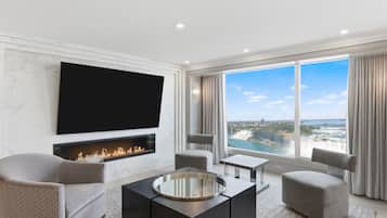 A modern living room with a fireplace, comfortable seating, a flat-screen TV, and a large window offering a scenic view.