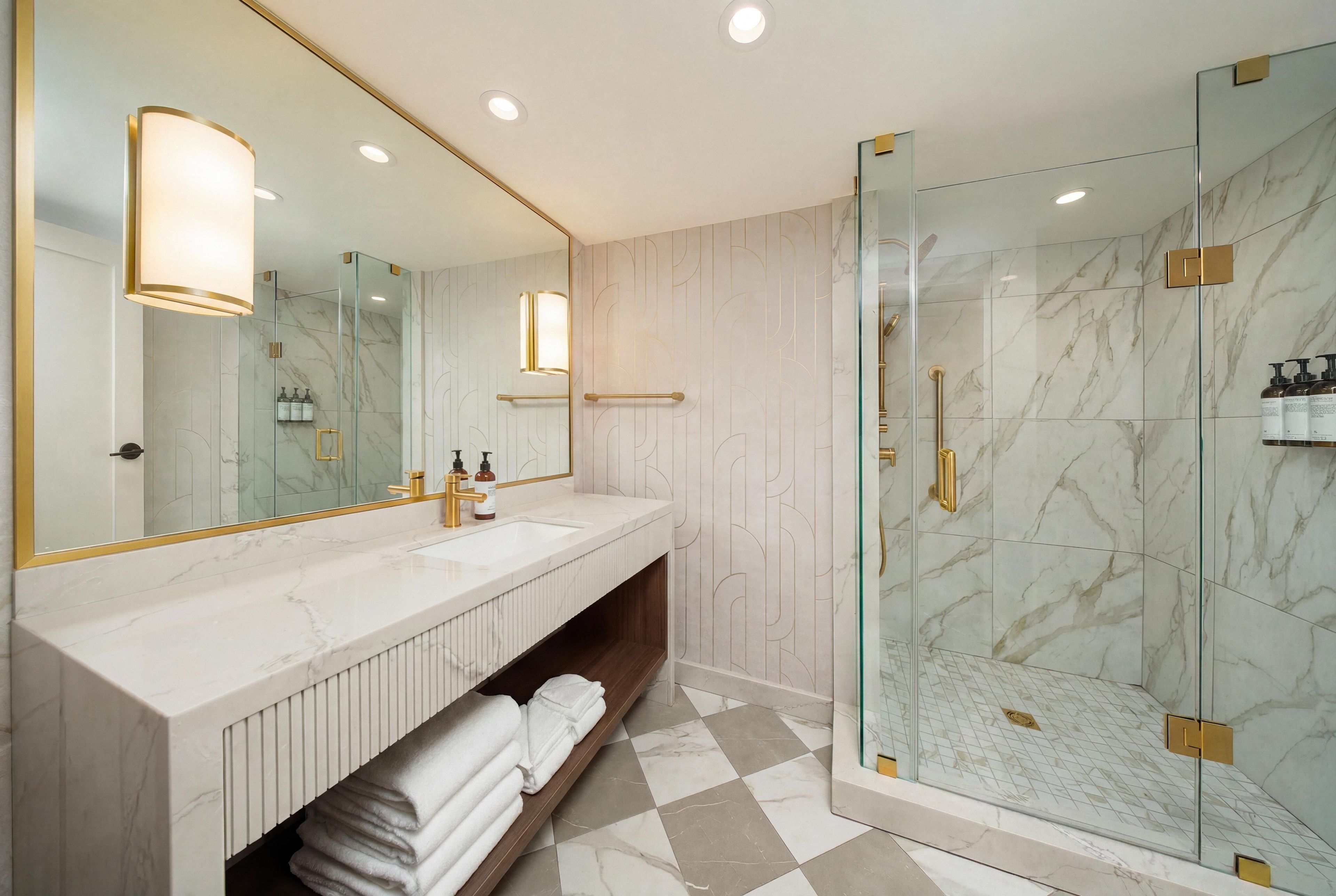 A modern bathroom with a marble vanity, a glass shower enclosure, and a large mirror.