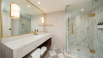 A modern bathroom with a marble vanity, a glass shower enclosure, and a large mirror.