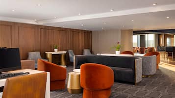 A modern hotel lobby with a seating area, a TV, and a reception desk.
